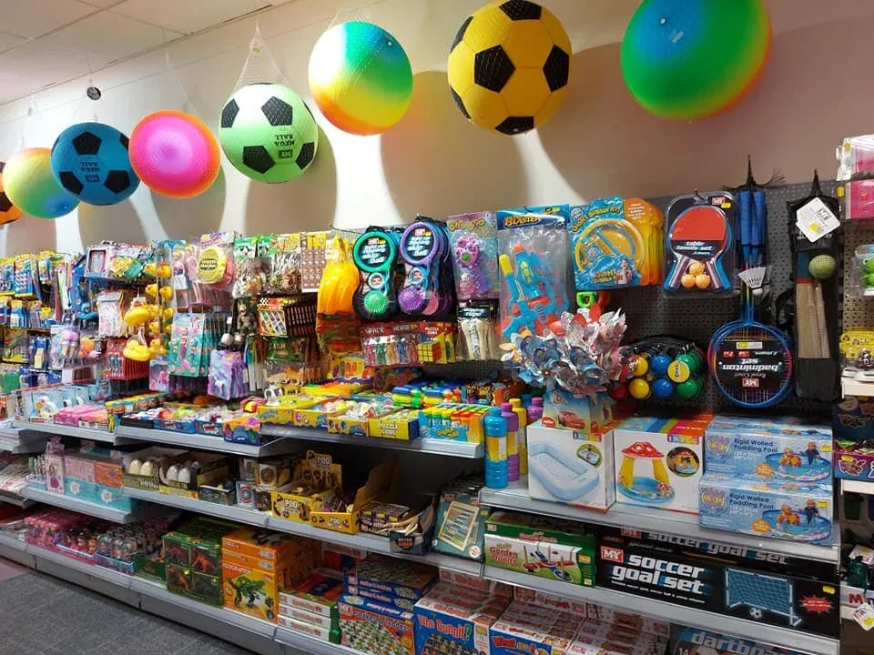 Footballs hanging above shelves of badminton sets, paddling pools and pocket money toys