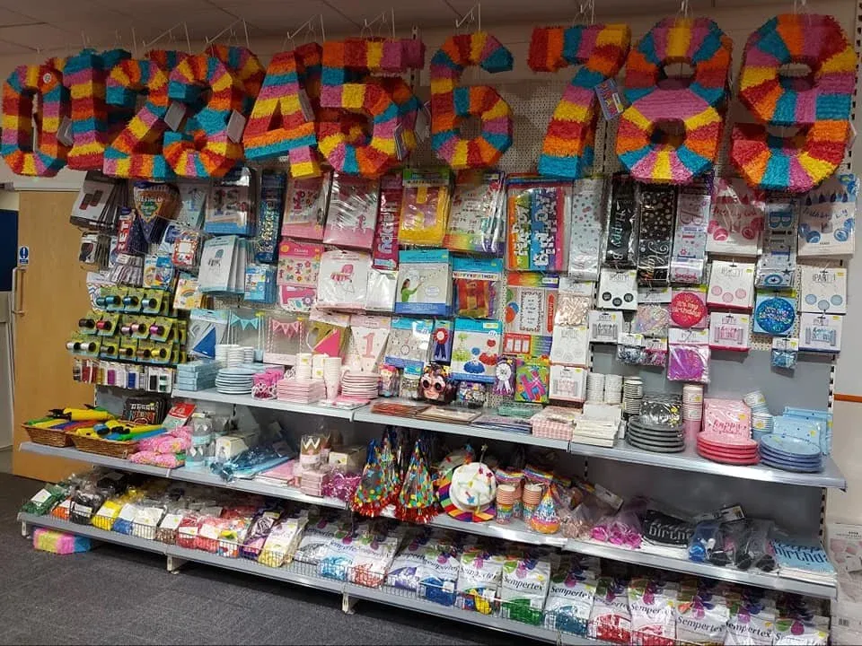 Rows of foil balloons and party decorations above shelves of gifts