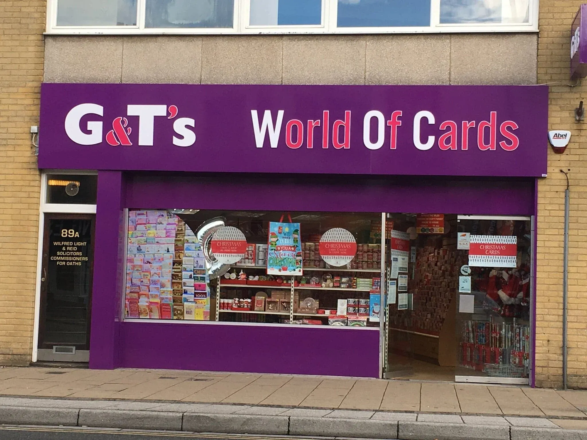The shopfront on the high street, its purple fascia above the window and Christmas cards in the display