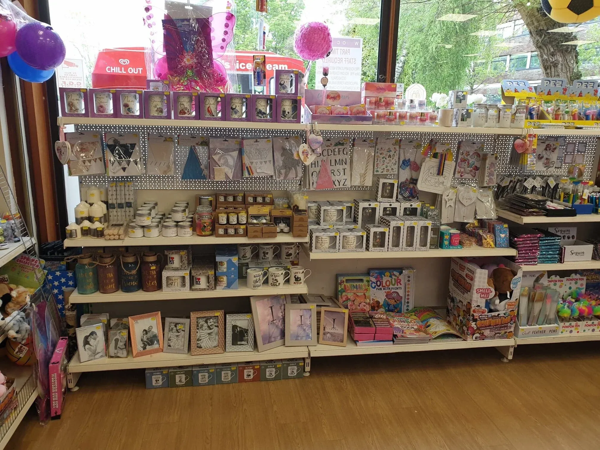 An aisle of party goods and gifts, daylight from the window at the end